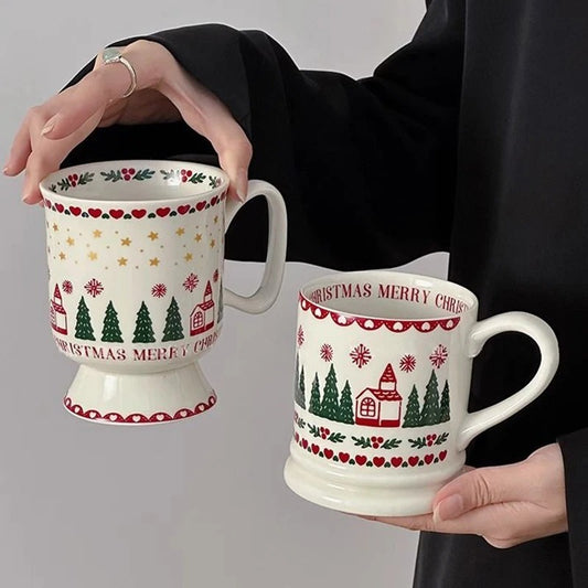 Two Christmas-themed mugs with decorative patterns held by a person against a neutral background.