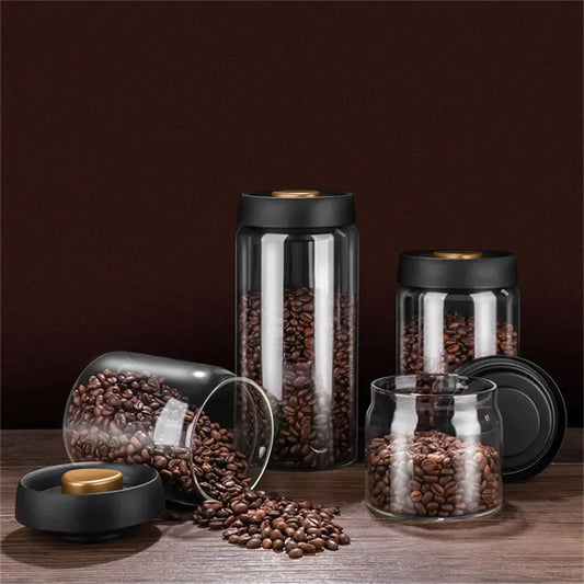 A trio of vacuum-sealed glass coffee canisters with spilled coffee beans. SHOP NOW