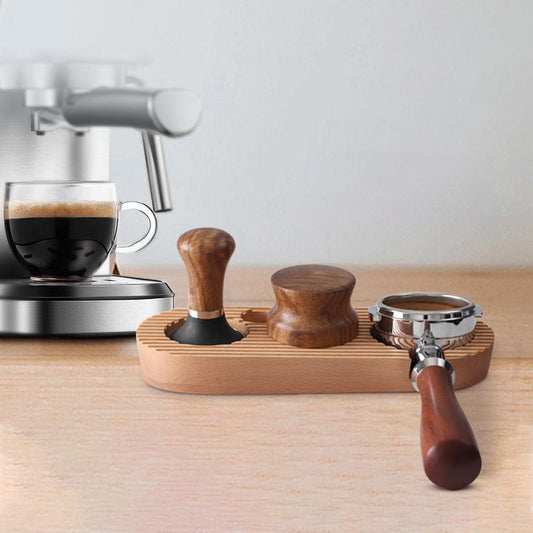 A wooden tamping station holding a portafilter and tamper on a kitchen countertop next to an espresso machine, demonstrating its practical use and stylish aesthetic. Shop now