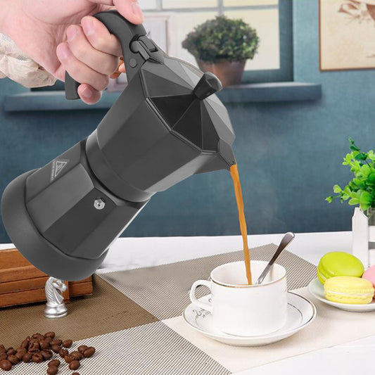 Hand pouring coffee from a portable coffee maker into a cup on a table with a blurred background. Shop now