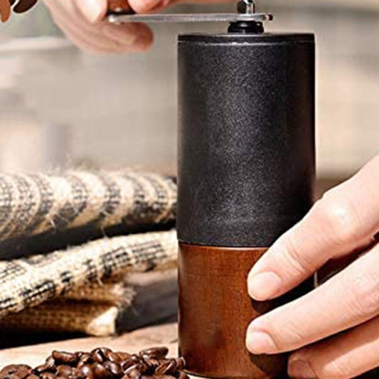 Grinding fresh coffee beans with a black and wood manual coffee grinder. Enhances coffee flavor.