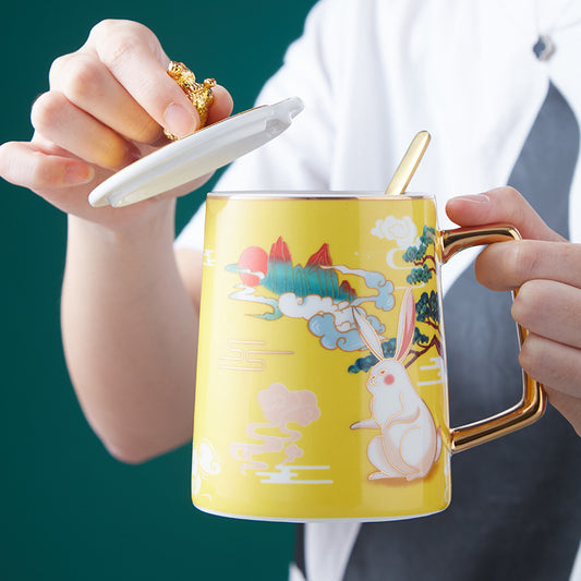 Person holding a yellow mug with rabbit design and spoon, against a green background