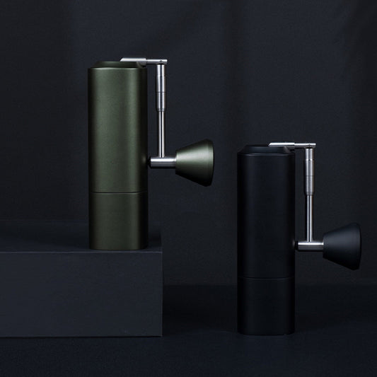 Two manual coffee grinders in olive green and matte black, highlighting sleek design and portability. #CoffeeGear #ManualGrinders #CoffeeTools #ProductPhotography #ModernCoffee