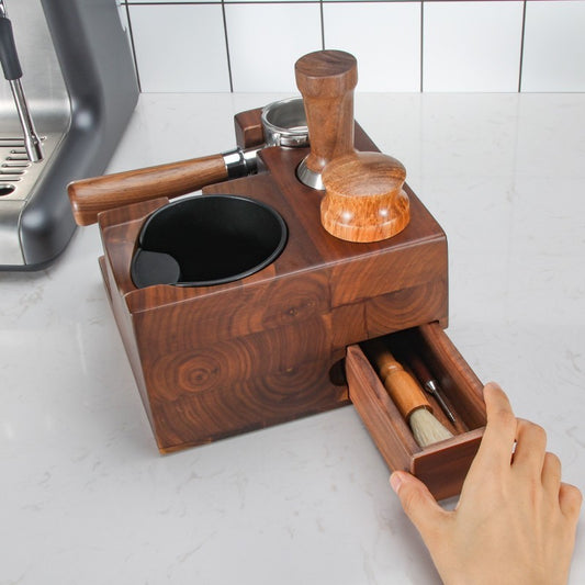 Wooden coffee grinder and brush set on a kitchen counter with a hand opening the drawer. Shop now