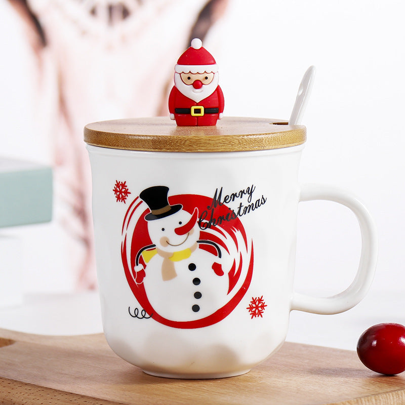 Christmas-themed mug with snowman design, wooden lid, and Santa figure on a wooden surface.