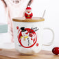 Christmas-themed mug with snowman design, wooden lid, and Santa figure on a wooden surface.