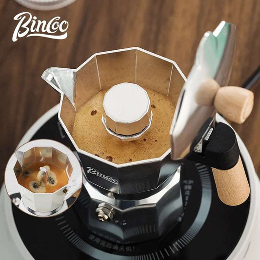 Classic black moka pot stovetop espresso maker with coffee cup and beans, perfect for home coffee brewing.