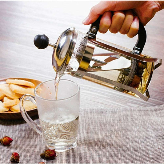 Hand pouring coffee from Classic Glass French Press into a mug, cozy home coffee brewing scene.