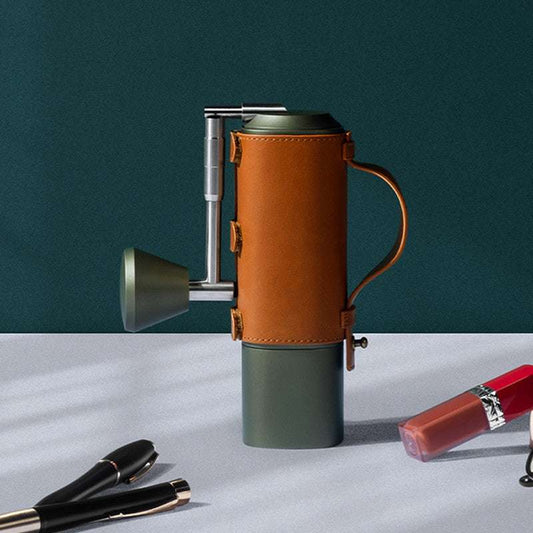 Olive green and tan leather manual coffee grinder, stylish and functional for daily coffee rituals. #CoffeeCulture #HandGrinder #CoffeeLife #Design #HomeDecor