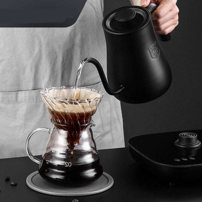 Pouring water from black gooseneck kettle into a glass coffee dripper for perfect pour-over brewing.