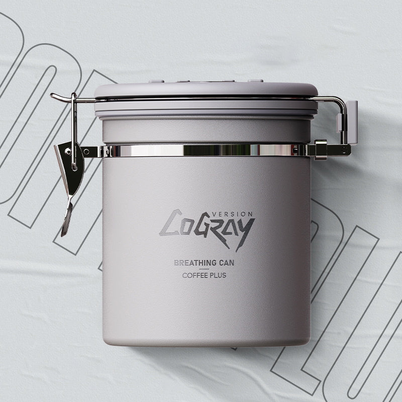 A grey Coffee Plus Breathing Canister, open with a 7g coffee scoop resting on a pile of fresh coffee beans. Another canister is visible in the background. Shop NOW