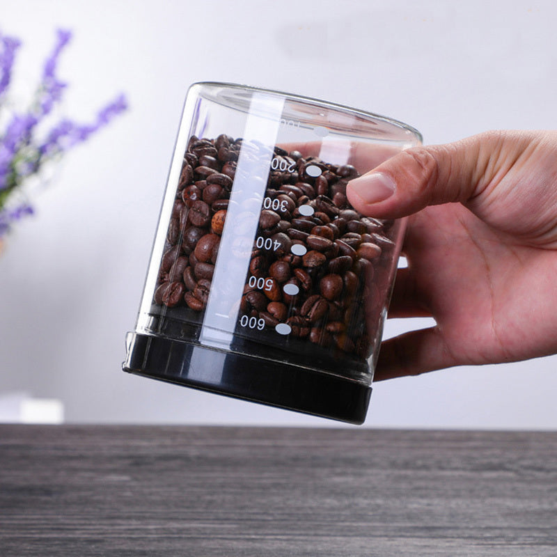Hand holding a 600ml airtight glass canister for coffee beans, showing its measurements and sleek design. Shop now