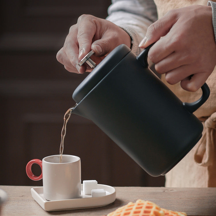 Pouring hot coffee from ceramic French press into a mug