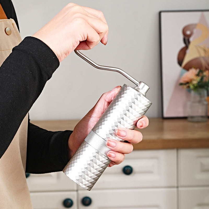 Hands using a silver manual coffee grinder to brew fresh coffee at home. Easy to use hand grinder. #HomeBarista #CoffeeTime #GrindFresh