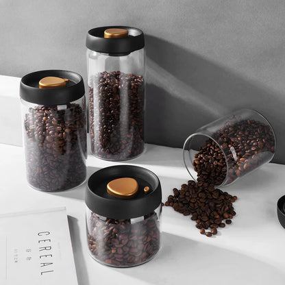 Glass jars with black lids containing coffee beans on a light surface. SHOP NOW