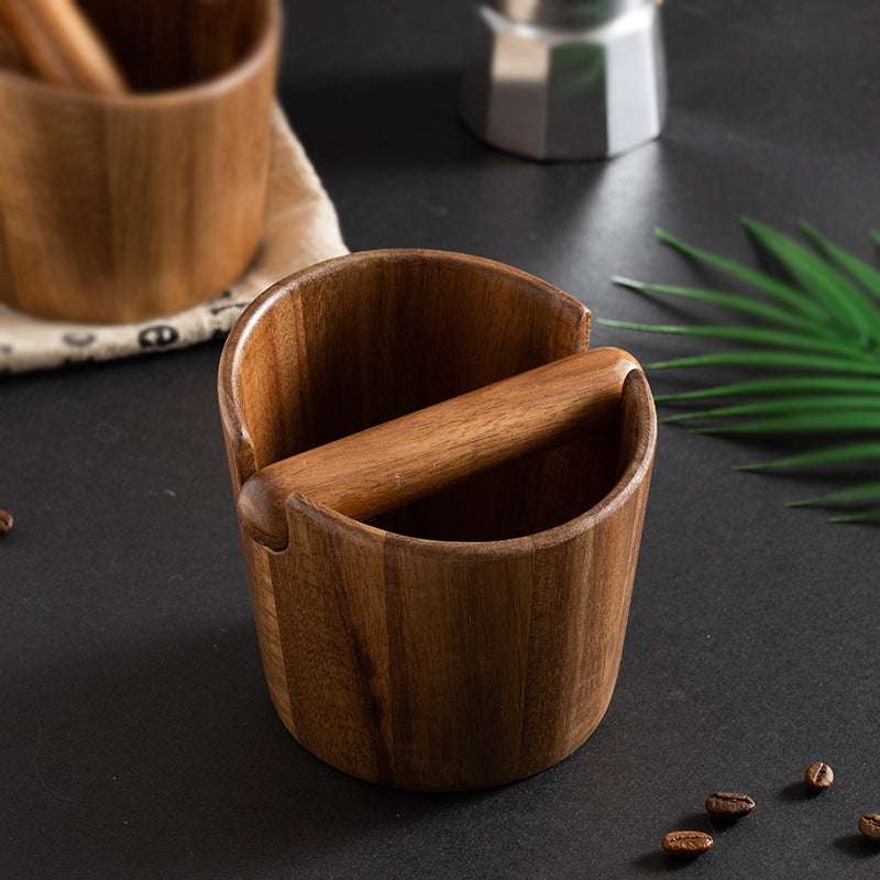 Wooden cup with a spoon on a dark surface with coffee beans and a plant leaf. Shop now
