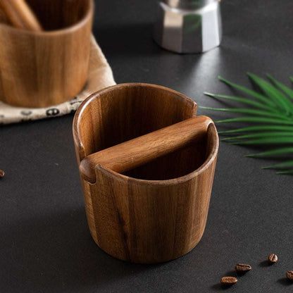 Wooden cup with a spoon on a dark surface with coffee beans and a plant leaf. Shop now