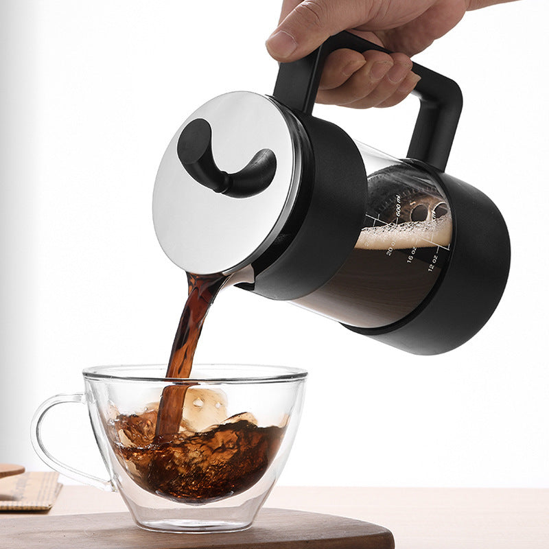 Black and clear glass coffee maker pouring coffee into a glass mug with ice.