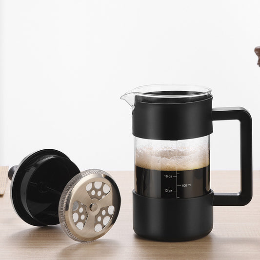An exploded view of a black and clear borosilicate glass French press coffee maker, showing its individual components: the stirring stick/frother, the lid, the plunger with its multi-layer filter system (mesh filter, coil, and retaining plate), and the main glass carafe with black base and handle, marked with volume measurements (12 oz, 16 oz, 20 oz, 24 oz, and 400 ml, 600 ml).