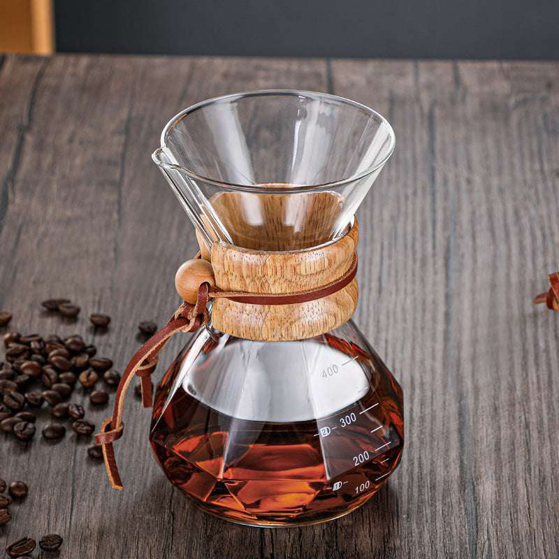 CHEMEX Glass coffee maker with wooden collar on a wooden surface with coffee beans, Set of three diamond glass pour-over coffee brewers with metal filters. Shop now