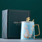 Decorative mug with rabbit design and gold handle next to a book titled 'Ceramic Fin' on a green background