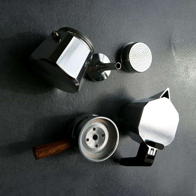 Moka Pot parts disassembled. Stovetop coffee maker components. Silver espresso pot and filter.