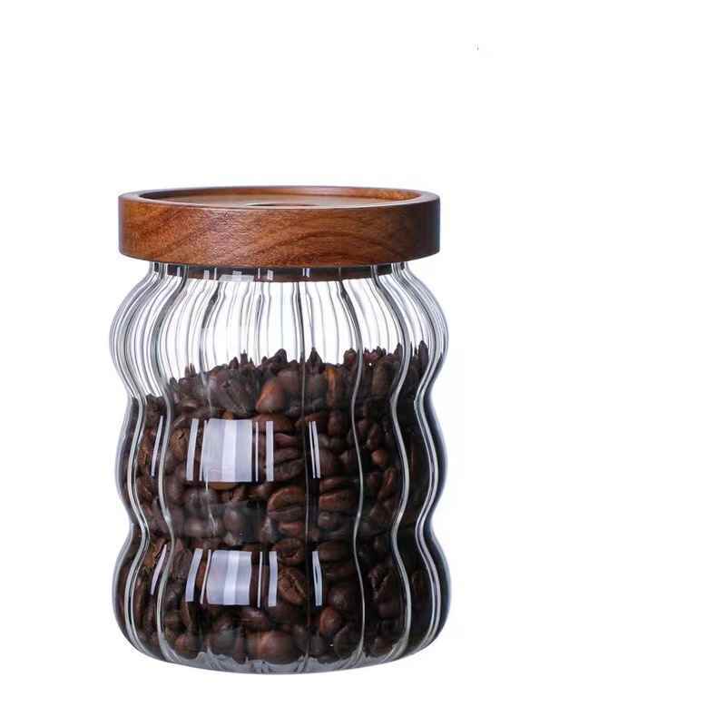 Glass jar with wavy design filled with coffee beans and a wooden lid Shop now
