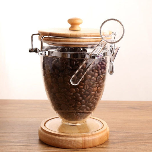 Glass jar with wooden lid and base filled with coffee beans on a wooden  Shop now surface.