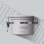A grey Coffee Plus Breathing Canister, open with a 7g coffee scoop resting on a pile of fresh coffee beans. Another canister is visible in the background.