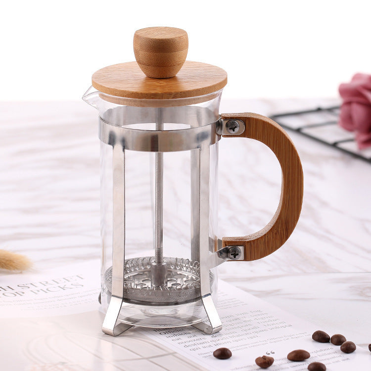 French press coffee maker with wooden lid and handle on a white surface with coffee beans. + Shop now + Free shipping
