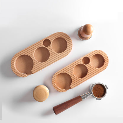 Overhead view of two wooden coffee tamping stations and various coffee accessories like tampers and portafilters, showcasing the product's versatility and elegant look. shop now