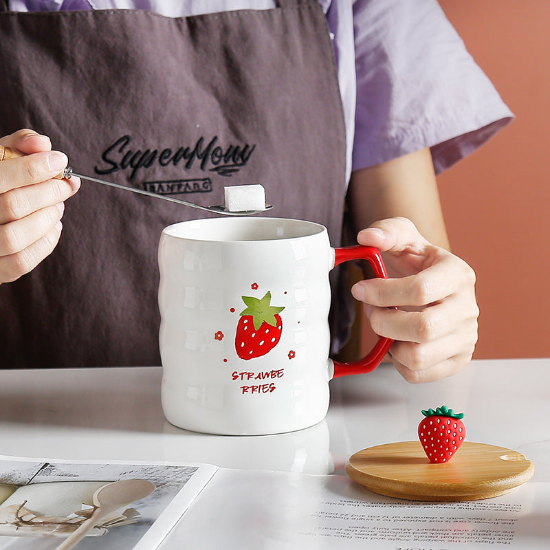 Person wearing a 'SuperMom' apron, holding a mug with strawberry design, and using a spoon. GIFT BOX PRESENT MUG