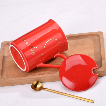 Red mug with heart design on a wooden tray with a gold spoon.