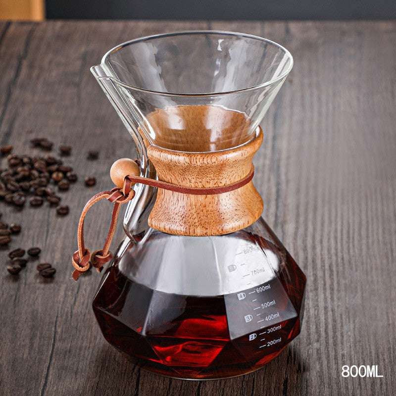 Glass coffee maker with wooden collar on a wooden surface with coffee beans