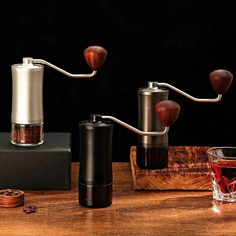 Three manual coffee grinders on a wooden surface with a dark background