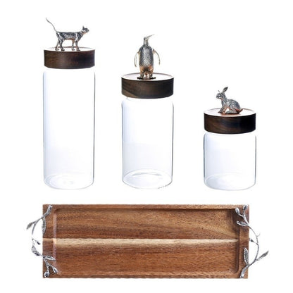 Three glass jars with animal figurines on lids and a wooden tray with metal handles 