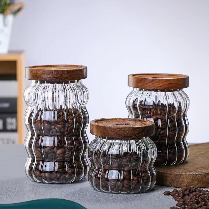 Three glass jars with wooden lids containing coffee beans on a light surface. 
SHOP NOW!