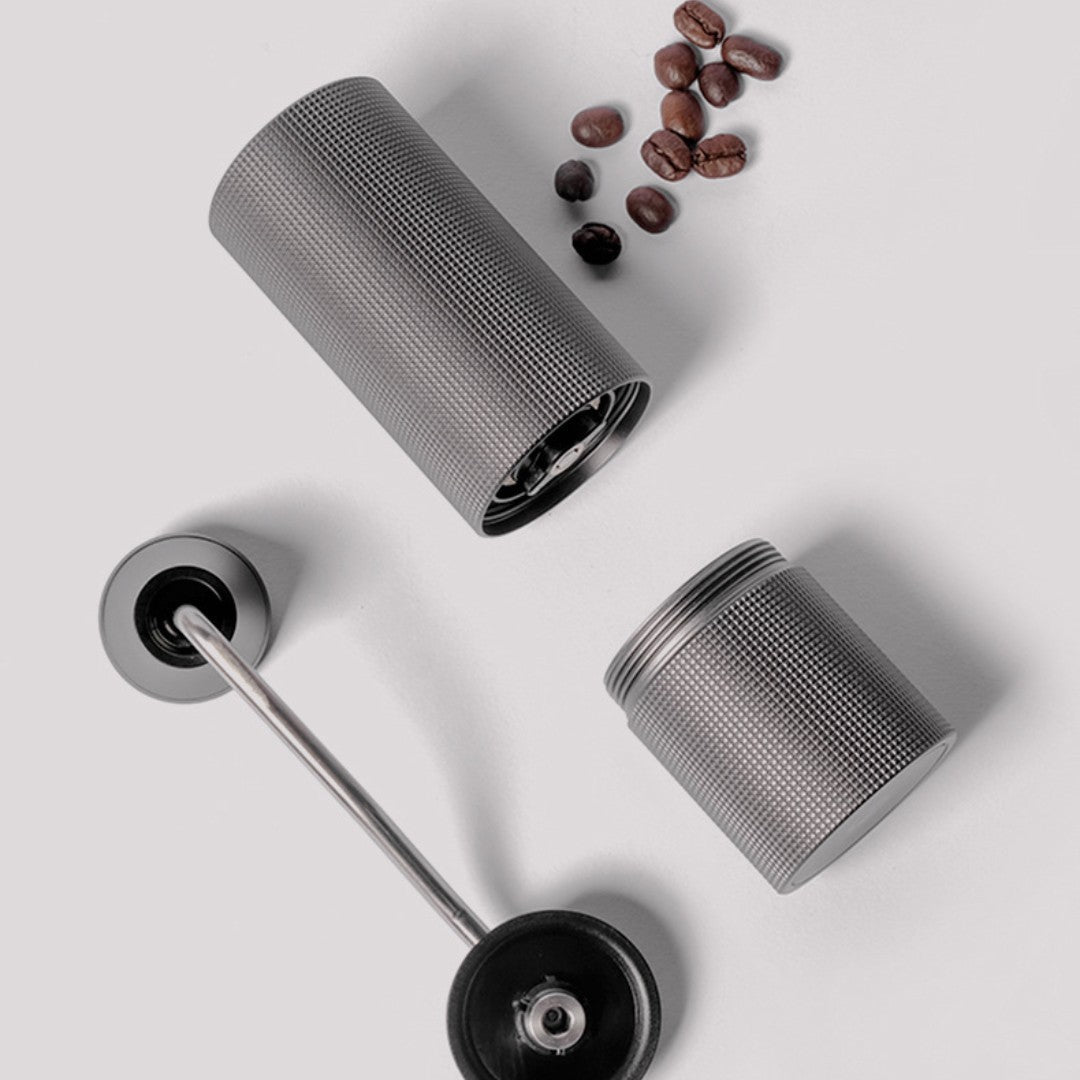 Disassembled manual coffee grinder (dark grey) with whole coffee beans. Shows easy assembly and quality design. #CoffeeAccessories #HomeBrewing