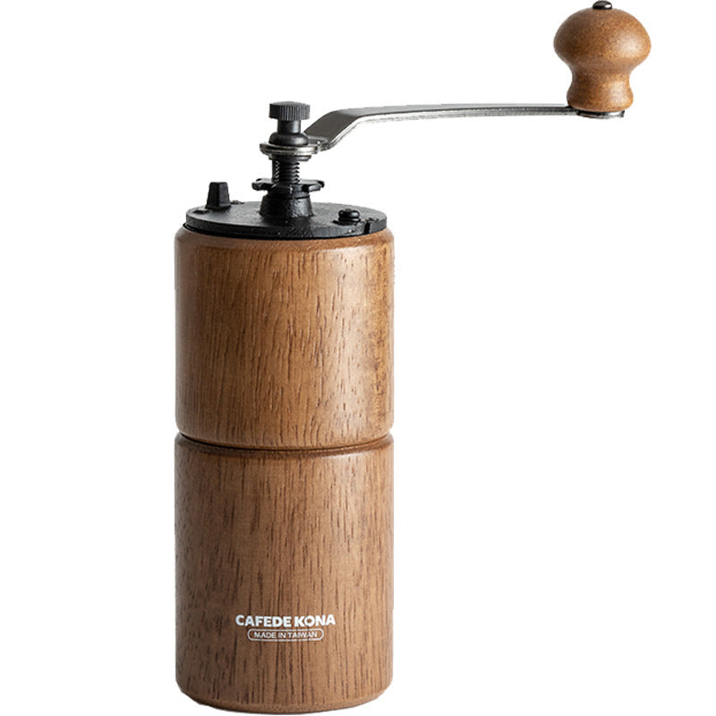 Two CAFÉDE KONA manual coffee grinders, one light wood upright, one dark wood lying down, on wood surface.