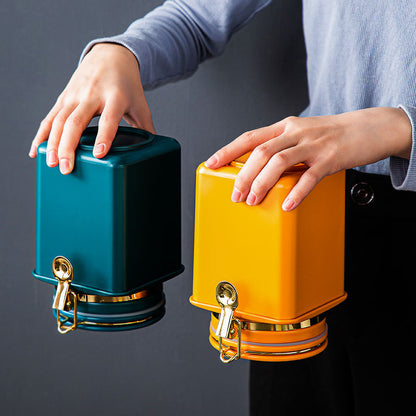 Two containers, one teal and one yellow, held by a person against a dark background.