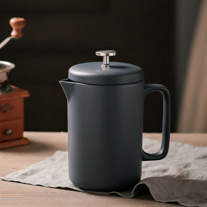 Black ceramic teapot on a wooden table with a blurred background