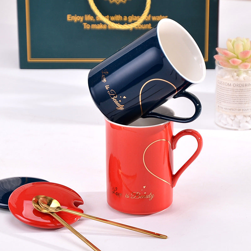 Two mugs, one red and one blue, with a heart design on a white surface.