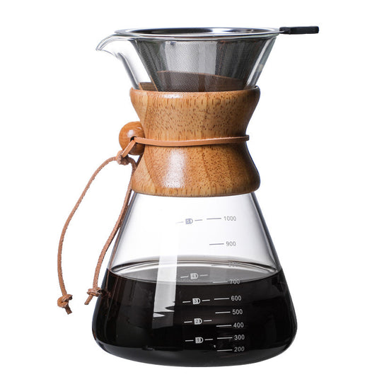 Close-up of a glass pour-over coffee maker with a wooden collar and stainless steel reusable filter, filled with dark coffee. The carafe shows measurements. FREE SHIPPING SHOP NOW
