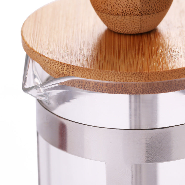 Clear glass container with wooden lid and metal base on a white background